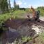 Ein Damm mit Holzspundwand und Mineralkern wird mit Torf überdeckt